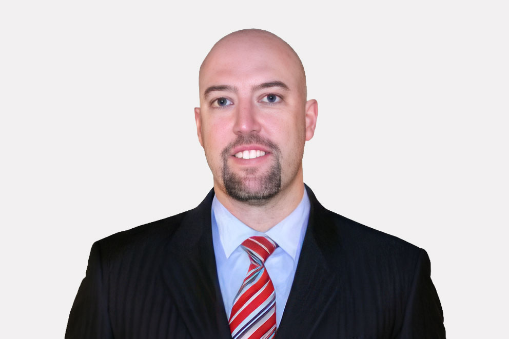 Dr. David G. Arthur smiling professionally in a dark suit with a white shirt and red-patterned tie against a neutral background.