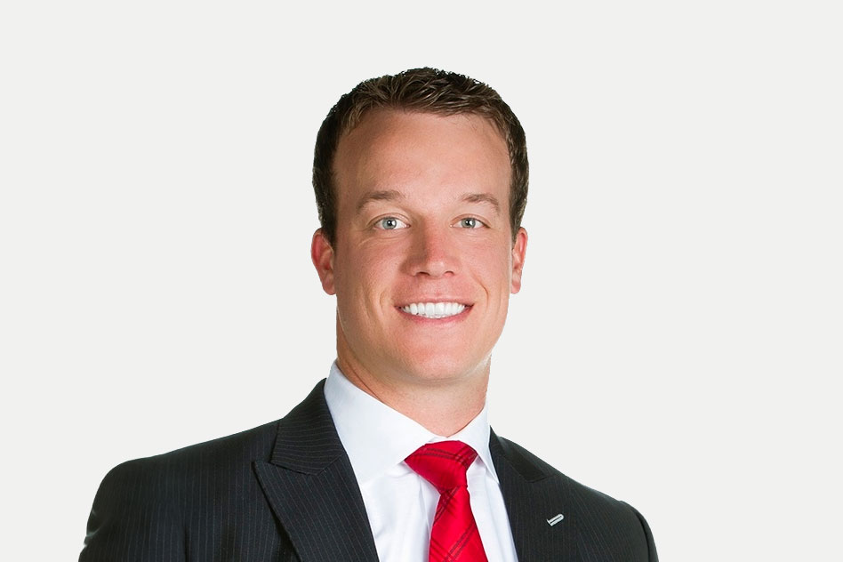 Joshua Redd smiling professionally in a dark suit with a white shirt and red tie against a neutral background as a speaker for Apex Seminars.